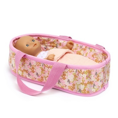 Boneca de plástico numa cama acolchoada rosa com padrão floral.