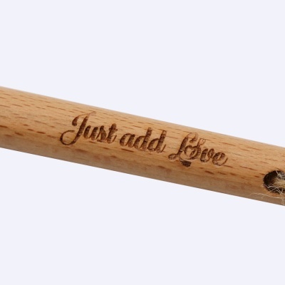 Cabo de madeira clara com gravação 'Just add Love' e cordão