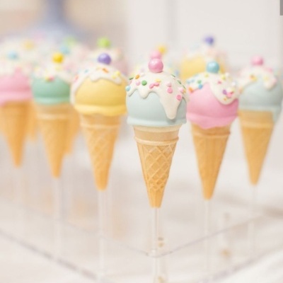 Cones de gelado decorativos em várias cores pastel com cobertura branca e bolinhas coloridas