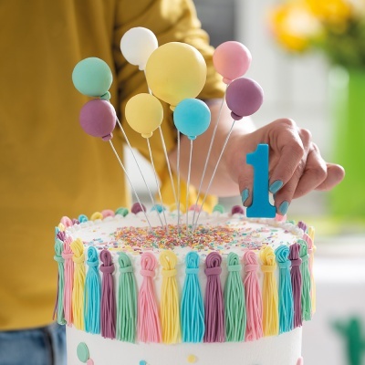 Bolo de aniversário decorado com franjas coloridas e balões em plástico