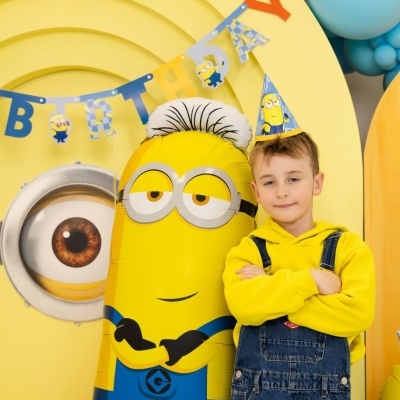 Balão Minion amarelo grande com menino vestido a condizer em festa colorida