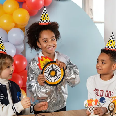 Crianças com chapéus de festa, balões coloridos e cupcakes decorados numa festa de aniversário.