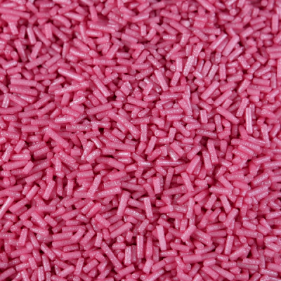 Confeites rosa pequenos em formato de bastão, textura brilhante