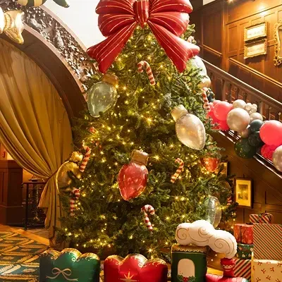 Árvore de Natal decorada com laço vermelho e comboio colorido na base