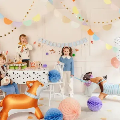 Festa infantil decorada com balões coloridos, bandeirolas, bolas de papel coloridas, mesa com toalha branca com bolinhas pretas e balões em forma de cães grandes