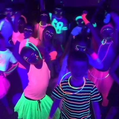 Crianças a usar roupas e acessórios fluorescentes numa festa com luz ultravioleta