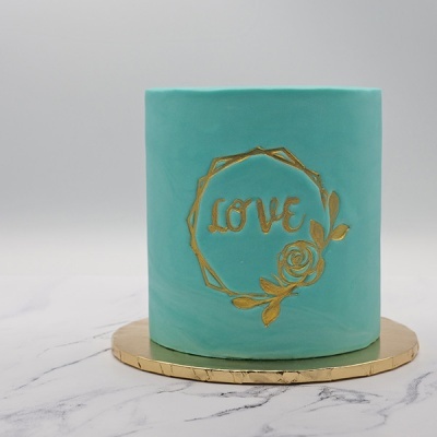Bolo azul turquesa com decoração dourada LOVE e rosa sobre base dourada