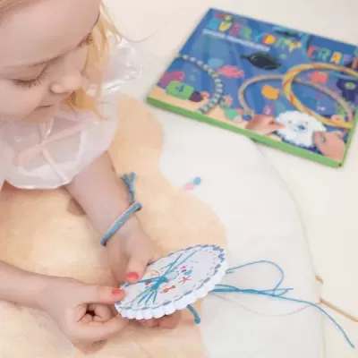 Menina fazendo trabalhos manuais de costura com caixa de artesanato ao lado
