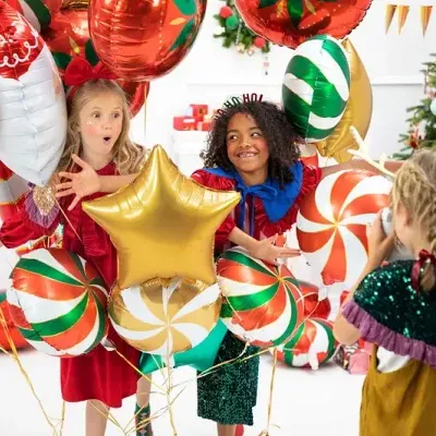 Crianças com balões de Natal coloridos em ambiente festivo
