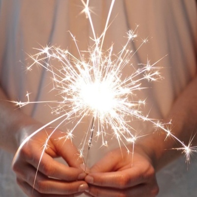 Pessoa segurando bengala de fogo acesa com faíscas brilhantes