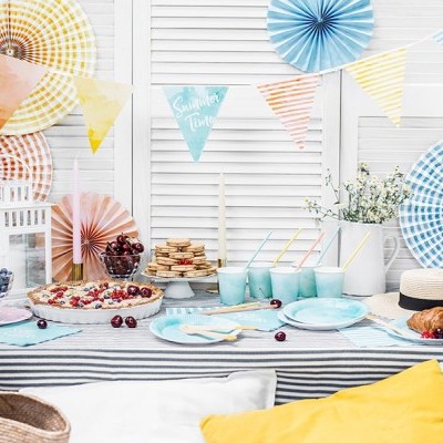 Mesa de festa com decoração colorida, comida e bebida, em ambiente interno com fundo branco