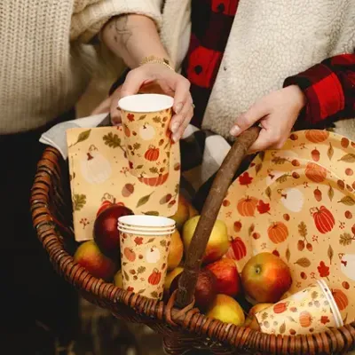 Cesto com maçãs e artigos de papelaria decorativos de outono com abóboras e folhas.