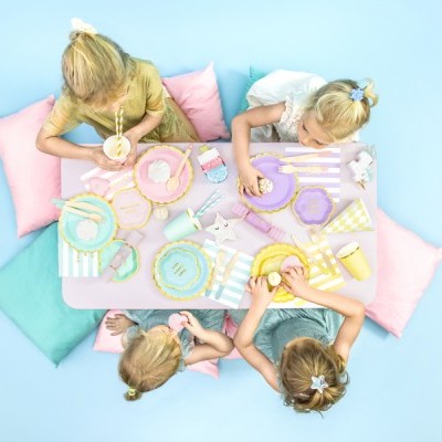 Crianças sentadas à mesa com decoração de festa infantil pastel