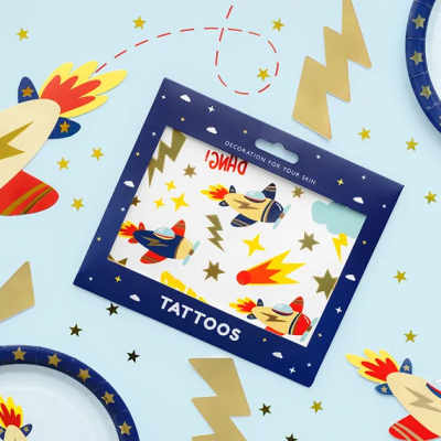 Conjunto de tatuagens temporárias com desenhos de aviões e pratos decorativos azuis com estrelas douradas