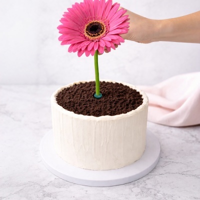 Bolo decorado com cobertura branca e flor rosa no centro