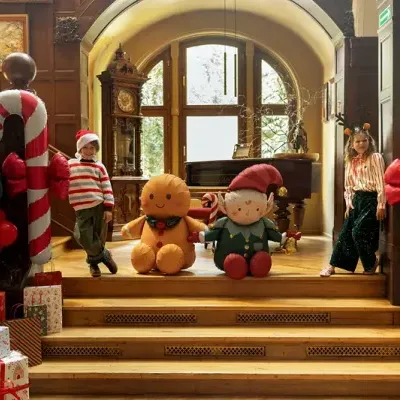 Decoração natalícia com bastões de doces insufláveis, balões e bonecos insufláveis em sala com escadaria de madeira e arcos de vidro