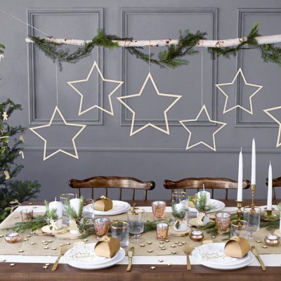 Mesa de jantar decorada para Natal com árvore e estrelas de madeira penduradas na parede
