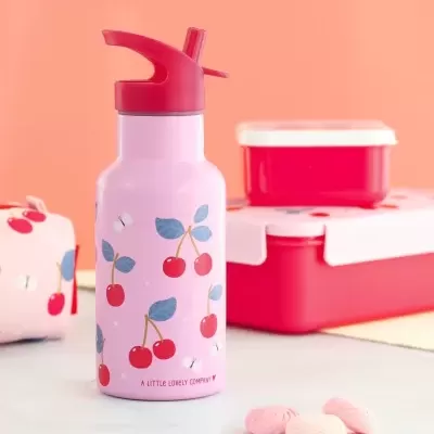 Garrafa rosa com padrão de cerejas e tampa vermelha ao lado de caixas vermelhas e biscoitos moles.