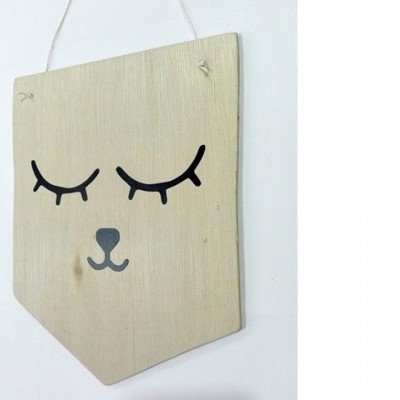 Placa decorativa em madeira clara com desenho de olhos fechados e focinho em preto