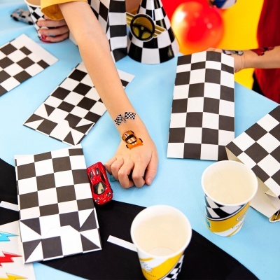 Mesa com decoração de festa temática de corrida com padrões de xadrez e carros de brinquedo