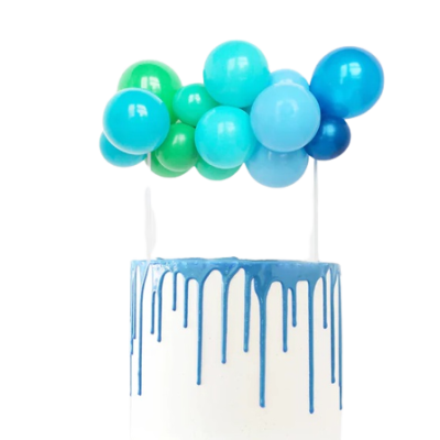Bolo branco com cobertura azul escorrendo e balões azuis e verdes no topo