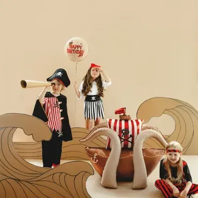 Crianças em fantasias de pirata com acessórios decorativos de ondas e navio
