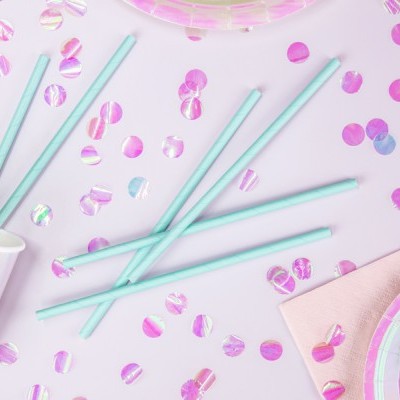 Canudos azuis claros rodeados de confetes rosa metálicos sobre superfície rosa