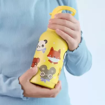 Garrafa amarela com desenhos de animais segurada por uma pessoa com camisola azul