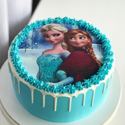Bolo decorado com glacê azul claro e imagem de personagens femininas na cobertura