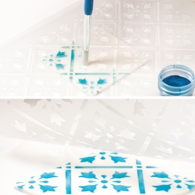 Stencil transparente com padrão floral e pó azul com pincel