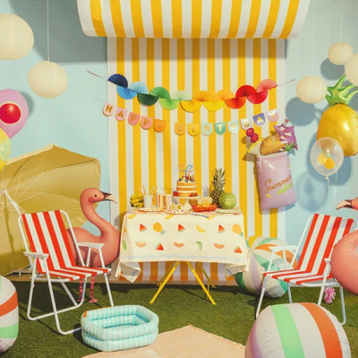 Mesa e decoração de festa com frutas, bolo, cadeiras riscas vermelhas e brancas, balões e flamingos insufláveis