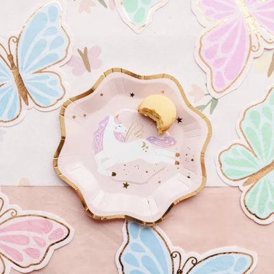 Prato de papel rosa com unicórnio e biscoito em cima, guardanapos com padrão de borboletas coloridas