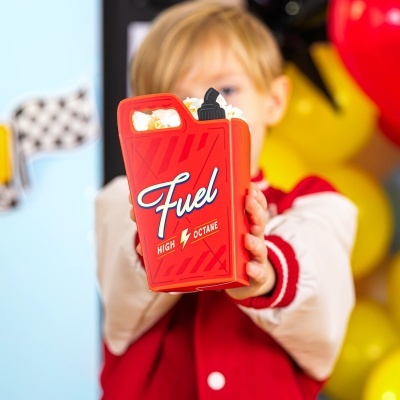 Caixa vermelha com texto Fuel cheia de pipocas nas mãos de uma criança