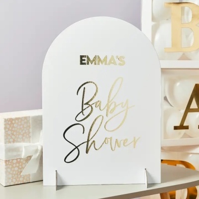 Cartão branco para Baby Shower com letras douradas e pretas num cenário com presentes e blocos de letras
