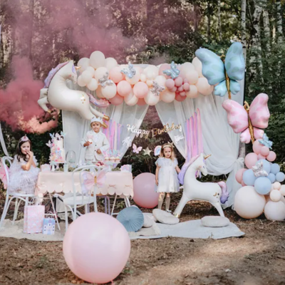 Decoração de festa infantil com balões pastel, unicórnios e borboletas ao ar livre