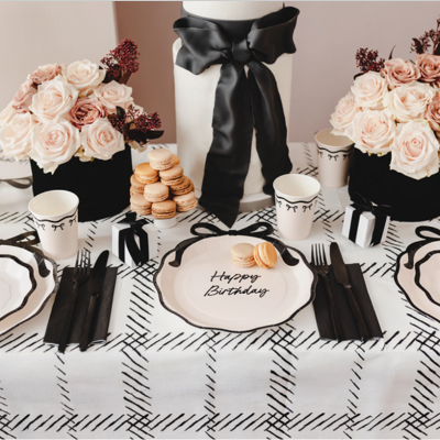 Mesa decorada para aniversário com flores, pratos e bolo com texto