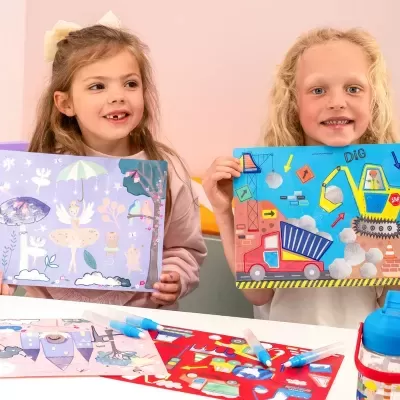 Duas crianças segurando desenhos coloridos com marcadores numa mesa