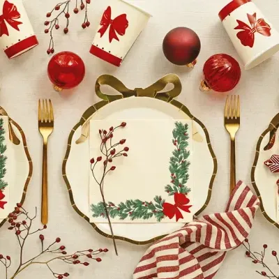 Mesa de Natal com pratos, guardanapos e copos decorados, bolas de Natal vermelhas e talheres dourados
