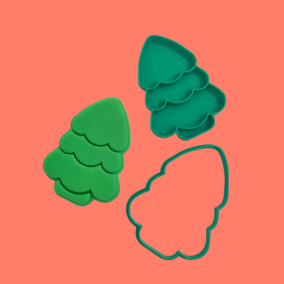 Cortadores de biscoito em forma de árvore de Natal verdes sobre fundo coral