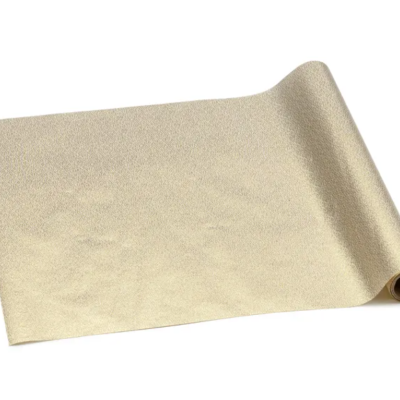 Rolo de material dourado parcialmente desenrolado sobre fundo branco