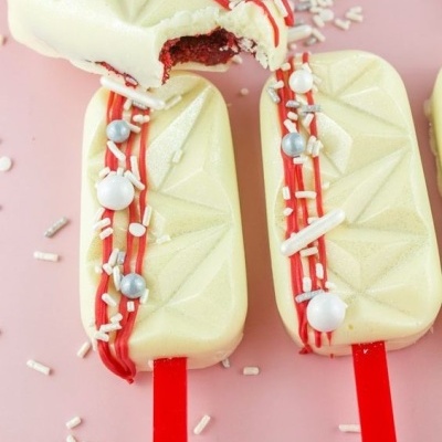 Gelados em barra com cobertura branca e decoração vermelha e prateada sobre fundo rosa
