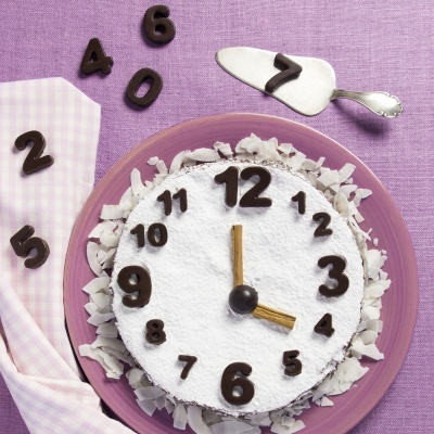 Bolo decorado com número de chocolate formando relógio em prato rosa