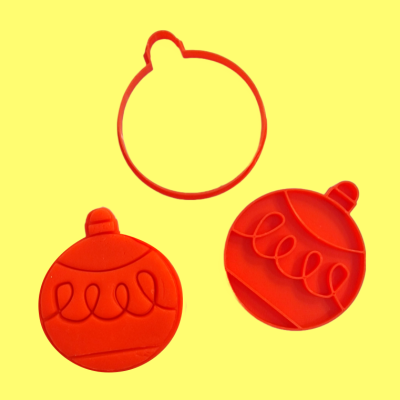 Cortadores e carimbos de biscoitos em forma de bola de Natal vermelhos sobre fundo amarelo