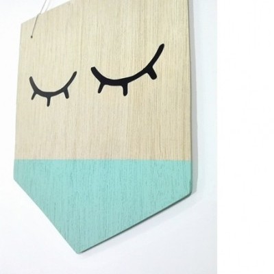 Placa decorativa em madeira com desenho de olhos fechados.