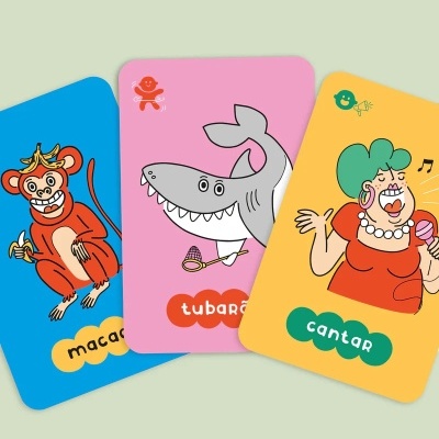 Cartas coloridas com desenhos de um macaco, um tubarão e uma pessoa a cantar.