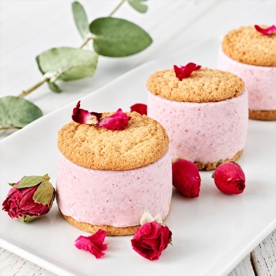 Bolos redondos rosa com biscoito e pétalas de rosa em prato branco