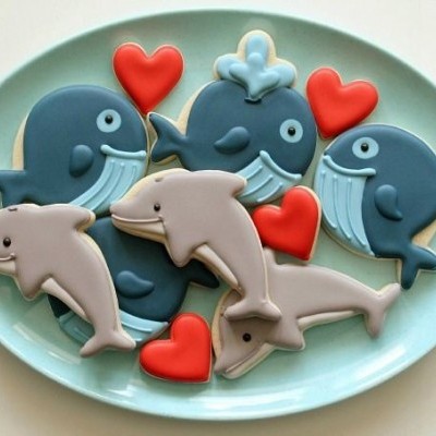 Biscoitos decorados em forma de golfinhos e corações num prato azul claro