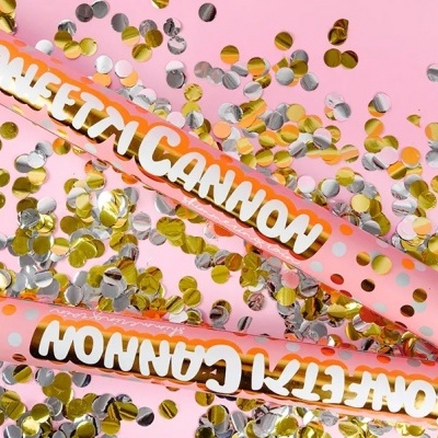 Dois canhões de confetes rosa claro com confetes metálicos dourados e prateados espalhados.