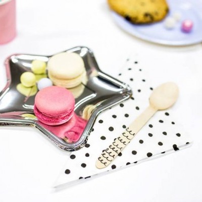 Prato estrela com macarons e doces variados, guardanapo com pontos pretos e colher de madeira