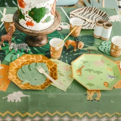 Mesa decorada com tema safari, pratos octogonais com animais, copos castanhos e brinquedos de animais